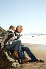 Senior Couple Sitting on a Rock at the Beach